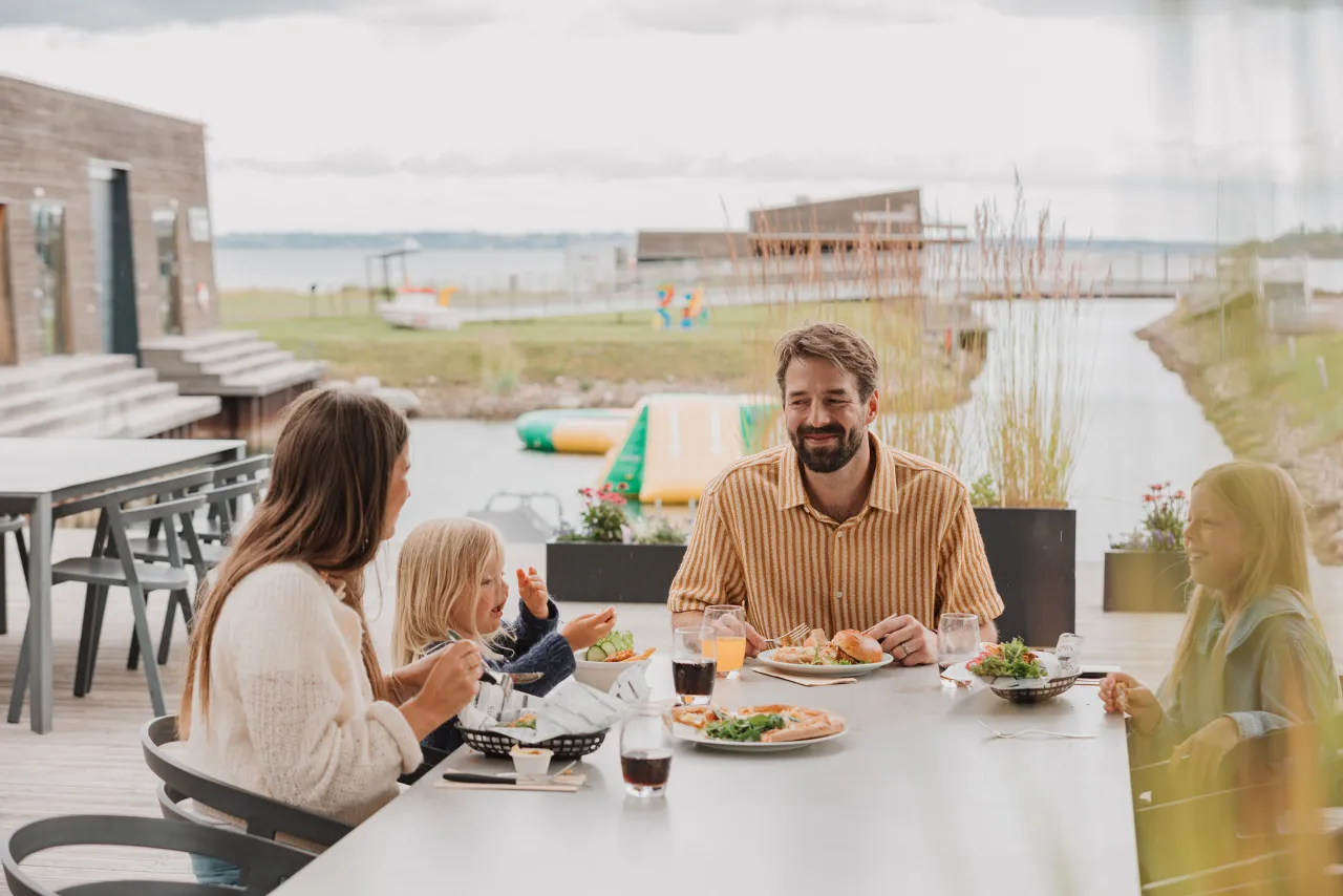Familie spiser på brygga sjø i bakgrunn